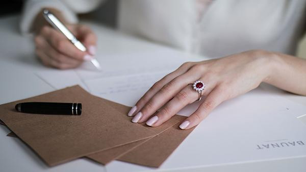 Mano con anello in oro bianco con rubino rosso e diamanti in stile halo