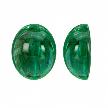 Deux pierres émeraude de forme ovale taillées en cabochon exposées côte à côte, mettant en valeur leur riche couleur verte et leur surface lisse.
