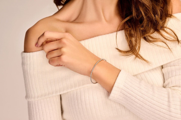 긴 머리를 한 여성이 손목에 스타일리시한 조합 팔찌를 착용하여 독특한 패션 감각을 뽐내고 있습니다.