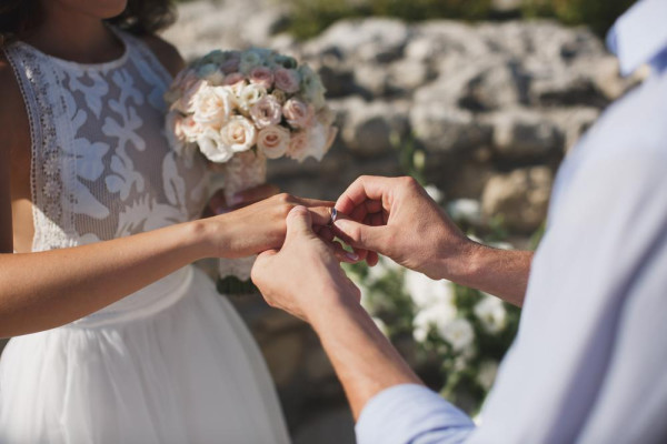 Man slides white gold ring onto the bride's finger. Find white gold wedding rings at BAUNAT 