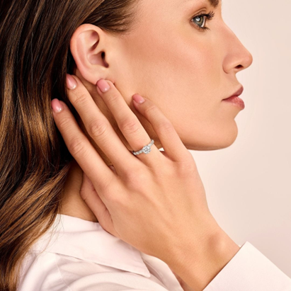 kendine güvenen kadınlar, daha küçük pırlantalarla çevrili tektaş ayarındaki mükemmel nişan yüzüğünü sergiliyor