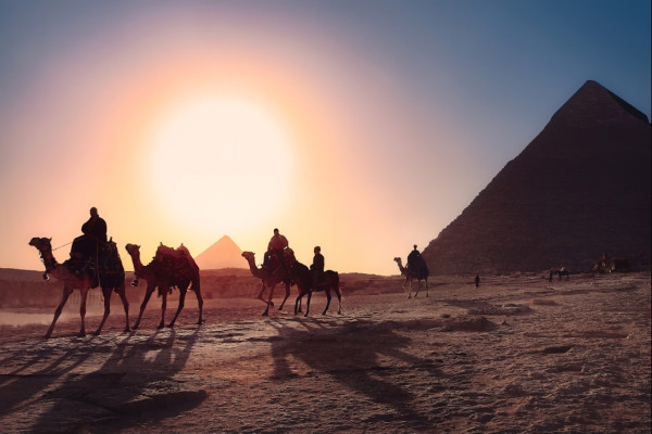 Die Sonne geht unter den Pyramiden von Gizeh unter und taucht den Himmel in leuchtenden Farben in dieser ikonischen Szene des alten Ägyptens.