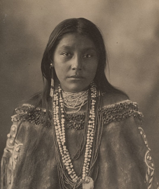 une femme amérindienne ornée d'un collier saisissant, reflétant la richesse de ses origines culturelles et de son identité