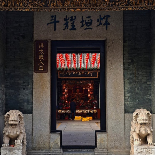 Un temple chinois se dresse, avec une statue de lion majestueuse gardant son entrée, mettant en valeur la culture traditionnelle chinoise