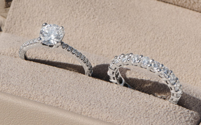 Platinum engagement ring with a round solitaire diamond and matching diamond pavé wedding band in a beige box