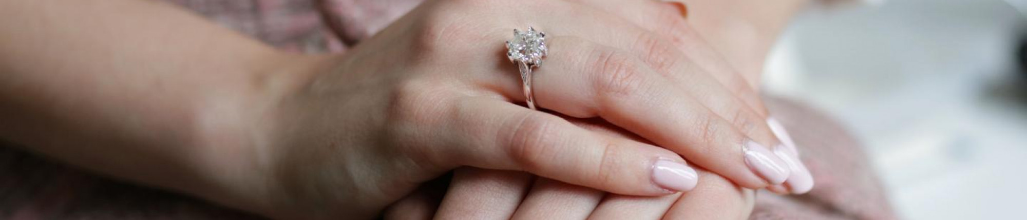 Hand met witgouden verlovingsring met ronde diamant in solitaire zetting