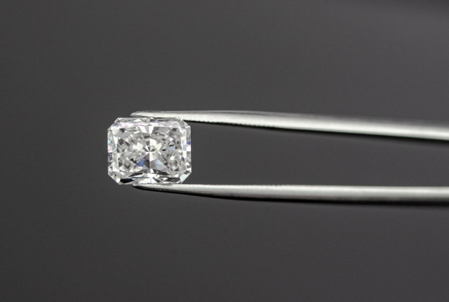 Radiant geslepen diamant in vierkante zetting, vastgehouden met metalen pincet De radiant cut diamant is de perfecte verlovingsring - BAUNAT