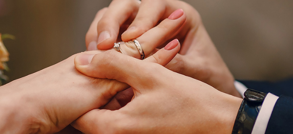Bruiloftshanden met witgouden trouwring en diamanten verlovingsring in close-up