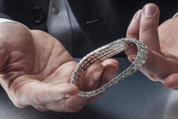 Man houdt een flexibele witgouden armband met smalle diamantzetting in beide handen