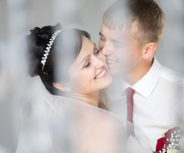 Bruidsfoto van een vrouw met een goudkleurige diadeem met kleine diamanten, naast haar partner.