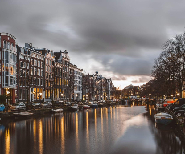 Amsterdamse gracht met historische herenhuizen, brug en weerspiegeling van stadslichten in het water