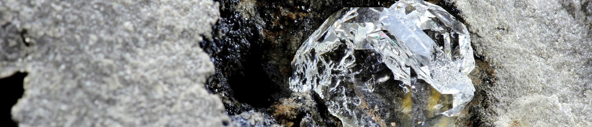 Ruwe diamant in grijze gesteente, zichtbaar in natuurlijke kristalvorm
