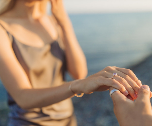 Two people wearing engagement rings and holding hands
