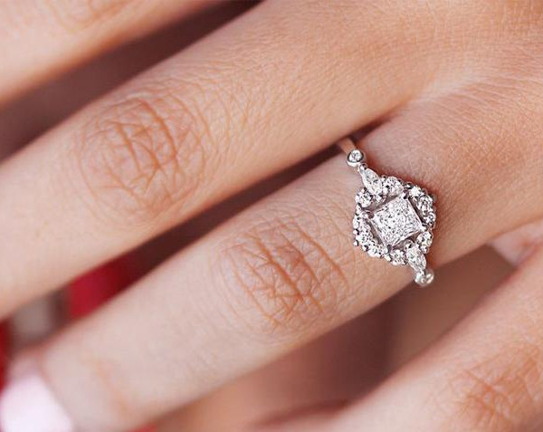 gouden ring met een vierkante diamant in halozetting, gedragen aan een vinger