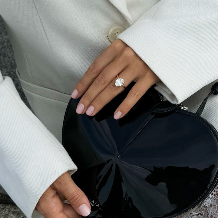 Rose gold solitaire engagement ring with a large round brilliant diamond on a woman’s hand