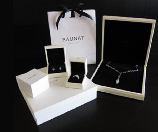 BAUNAT 珠宝礼盒陈列图，黑色丝带礼袋搭配白色首饰盒，展示钻石项链、耳钉和戒指等高级珠宝包装