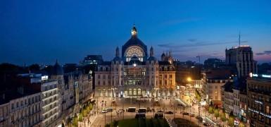 夜景中的城市广场与中央穹顶建筑全景，周围环绕古典楼群与街道灯光，蓝色暮色天空下呈现欧洲都市风貌。